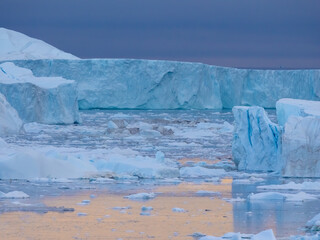 Enormous icebergs seen during the midnight sun, Disko Bay north of the Artic Circle near Ilulissat,...