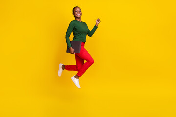 Fototapeta na wymiar Full length photo of cute adorable woman wear green shirt holding device jumping empty space isolated yellow color background