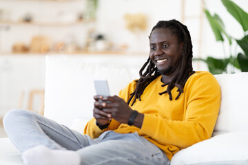 Nice App. Smiling African American Guy Relaxing In Chair With Smartphone
