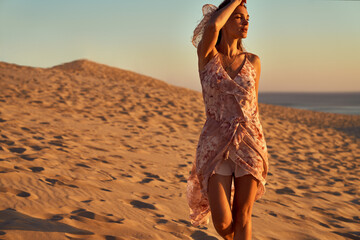 Young fashionable woman walking on the beach during the sunset