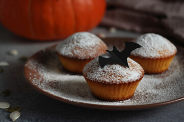 powdered muffins with pumpkin, pumpkin seeds and black bat