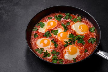 Shakshuka, a dish with fried eggs with tomato sauce, sweet pepper, garlic, onions, spices and herbs