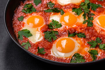 Shakshuka, a dish with fried eggs with tomato sauce, sweet pepper, garlic, onions, spices and herbs