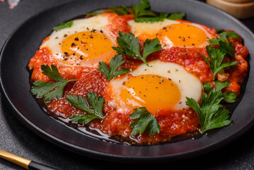 Shakshuka, a dish with fried eggs with tomato sauce, sweet pepper, garlic, onions, spices and herbs