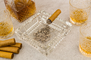 Fototapeta na wymiar Cigar in ashtray on a table with whiskey in bar