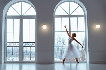 ballerina in long white tulle skirt, crouching in bow pose,