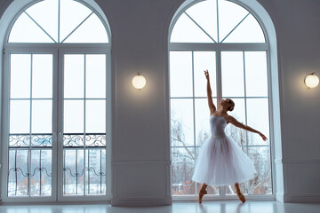 ballerina in long white tulle skirt, crouching in bow pose,