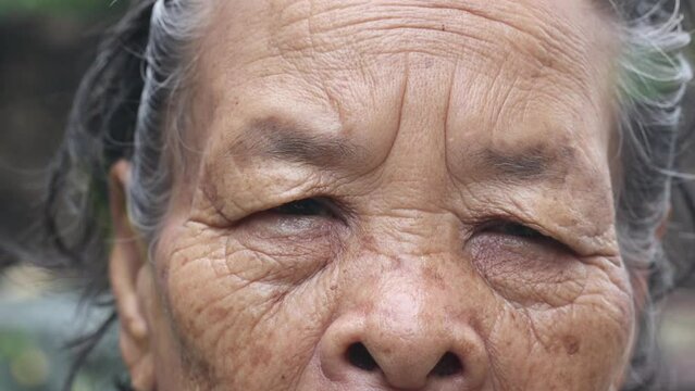 Old woman's face and eyes Large wrinkles on face of Asian elderly woman in Thailand, close-up face, elderly looking into the distance eyes that express feelings