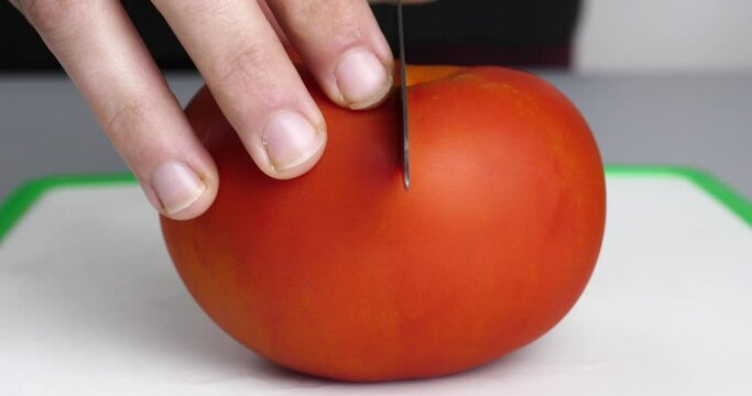 cutting a big red tomato in half closeup. High quality 4k footage