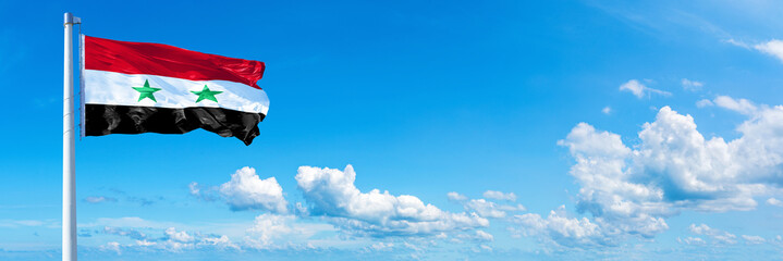 Syria flag waving on a blue sky in beautiful clouds - Horizontal banner