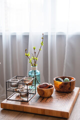 Home interior - bowls with stones, candles and blue bottle with spring branches