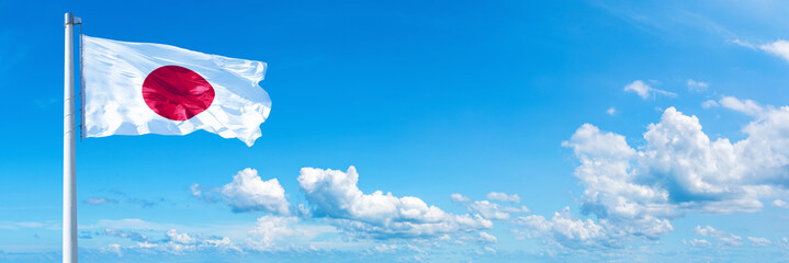 Japan flag waving on a blue sky in beautiful clouds - Horizontal banner