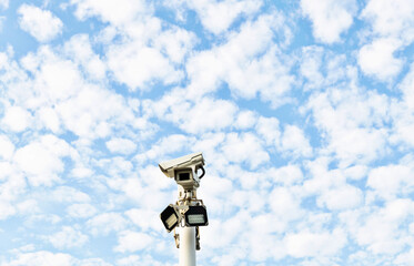 Security cameras under cloud sky
