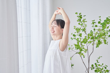 明るい窓辺で深呼吸する女性