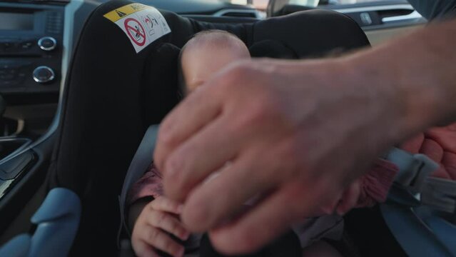 Portrait of cute baby and father fastens safety belts in a car seat during a joint trip with a kid in the car. Kissing. Funny child. Childhood. Happy. Slow motion