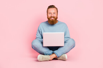Full length photo o f cheerful man sit floor use wireless netbook isolated on pink color background