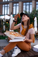 Girl eating pizza on the street, food delivery