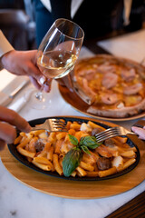 many hands with forks eat pasta