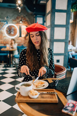 beautiful girl in a red beret eats a business lunch
