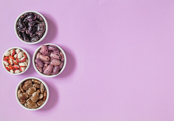White bowl with organic heirloom beans on a purple background. Scarlet runner beans, anasazi beans. Top view. Copy space.