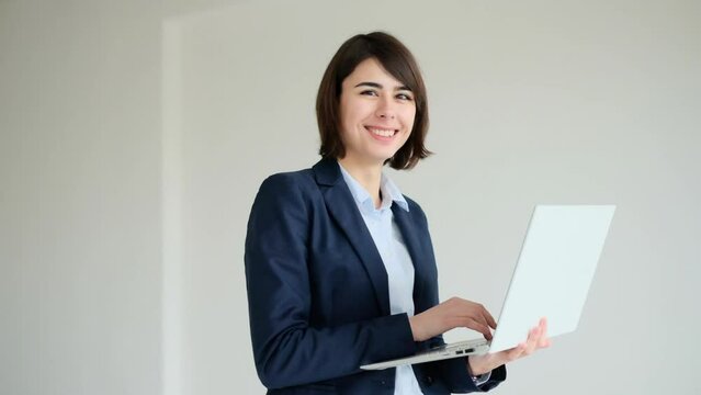 Business woman standing with laptop and smiling 