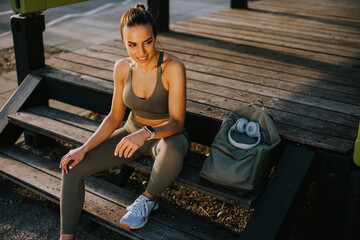 Young attractive female  runner taking break after jogging outdoors