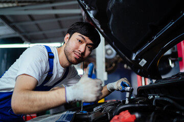 Fototapeta na wymiar Male mechanic checking the engine system in the car, service, maintenance. Auto mechanic repairing engine. A mechanic is fixing the engine of a car at his factory. Concept of auto service