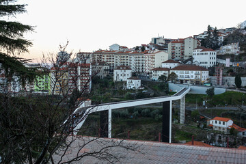 Covilha, Portugal, march 17 2014; General view of the Ribeira da Carpinteira crossed by the Carrilho da Graça pedestrian bridge at sunset with the city in the background