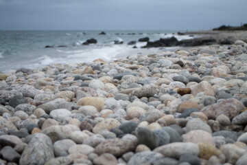 Gloomy mood ocean scene, beach rocks in the foreground, choppy waves in the background. For a narrative, composite, etc. background