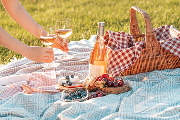 Romantic picnic setting with rose wine, snacks and wicker basket.