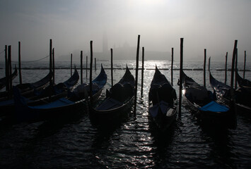 Moored gondolas in front of San Giorgio Maggiore made ghostly by fog on a freezing late December morning (Venice, Italy).