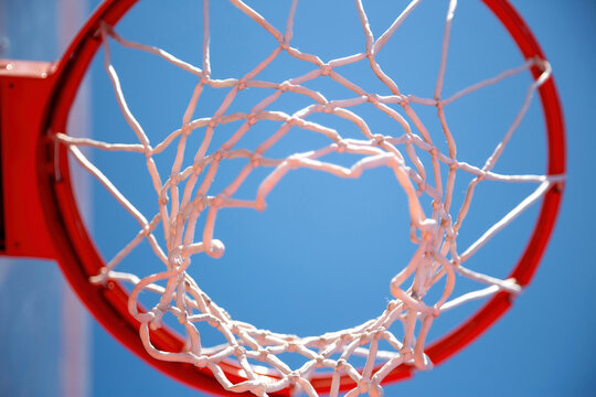 Basketball hoop, red ring and net, blue sky background, underview