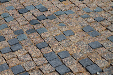 New cobblestone pavement made of brown and black granite stones