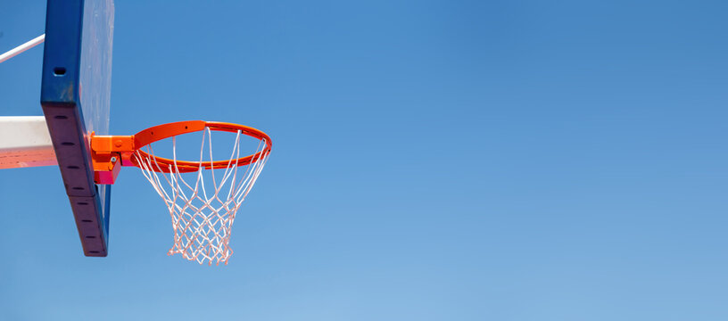 Basketball hoop, red ring and net on backboard, clear blue sky