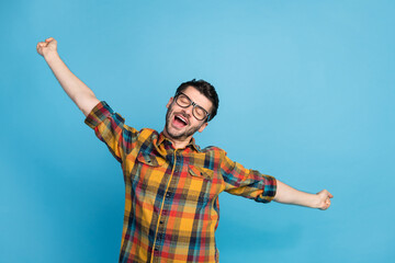 Fototapeta na wymiar Photo of peaceful handsome man in eyewear dressed checkered shirt stretching slumbering closed eyes isolated on blue color background