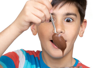 Photo of adorable young happy boy looking at camera.Isolated on the white background. Cheerful little boy eating chocolate spread from jar by spoon and having fun