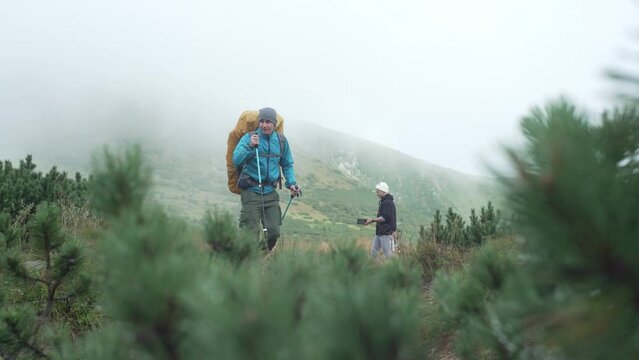A tourist climbs the mountains in bad weather. Smoky mountains in the fog of raindrops. A guy with a backpack on a hike. High quality 4k footage