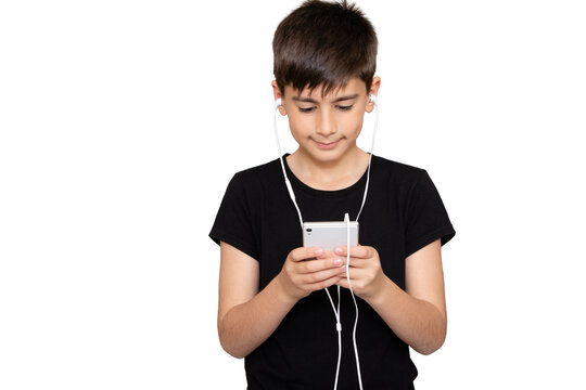 Cheerful young boy listening to the music in headphones and mobile phone isolated over white background