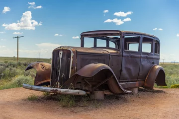 Foto op Plexiglas A weathered and rusting Studebaker antique car sitting along the old Route 66 Highway. © Picturellarious