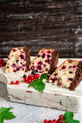 pieces of sliced berry fruit cake with black and red currants on a gray concrete background 4