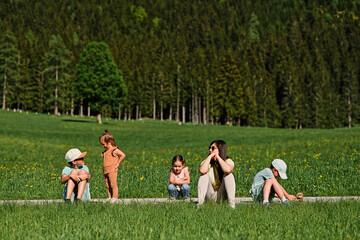 Mother sitting with children on path in alpine meadow at Untertauern, Austria.