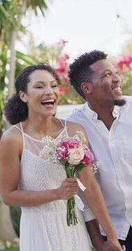 Vertical video of happy married african american couple with flowers