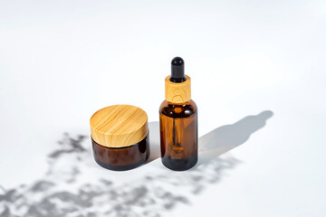 Serum and moisturizer cream on white background with flower shadows. Beauty products mockup. Healthcare skincare concept
