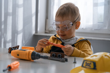 Child play with work tools at home, dreams to be an engineer. Little boy builder. Education, and imagination, purposefulness concept - 535333710