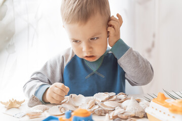 Child play with sea shells and boats. Summer vacation and travel concept. Kid play with lifebuoy and starfish