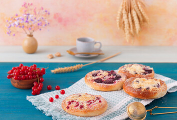 Baked pies with summer fruits, currants, plums, blackberries, blueberries and crumble, blue wooden table, low angle of view, no people.