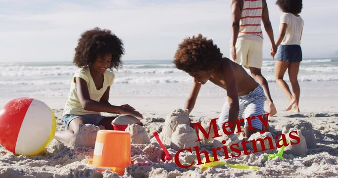 Animation of merry christmas over happy african american siblings playing with sand on beach