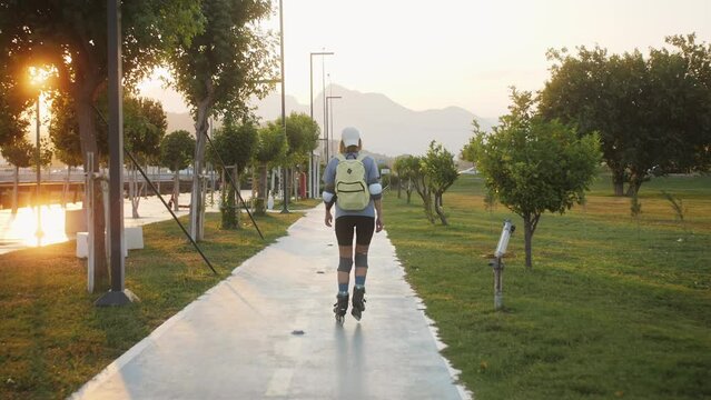 Woman rollerblade on. Young athletic girl rollerblading quickly rides through the park.