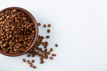 Medium rare coffee beans in rustic clay cup on white isolated background