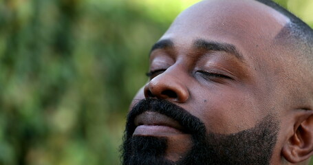 Positive African breathing fresh air outside, happy close-up face smiling